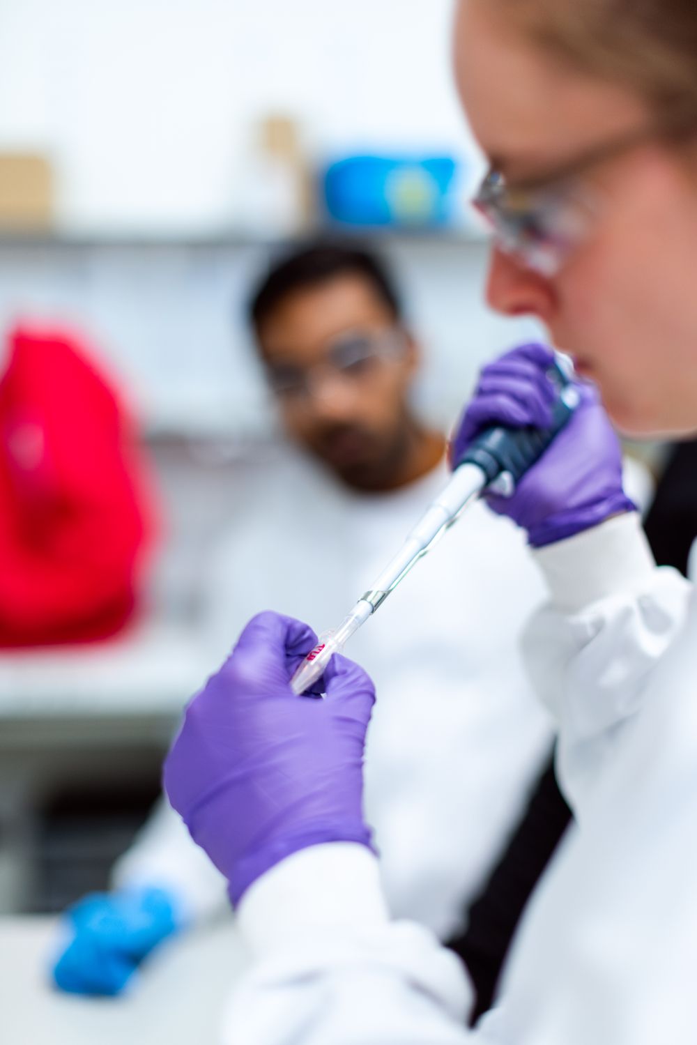 Researcher in protective gear using a pipette in a laboratory